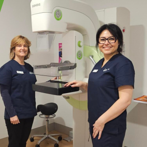 Two women radiographers, standing beside a mamography machine