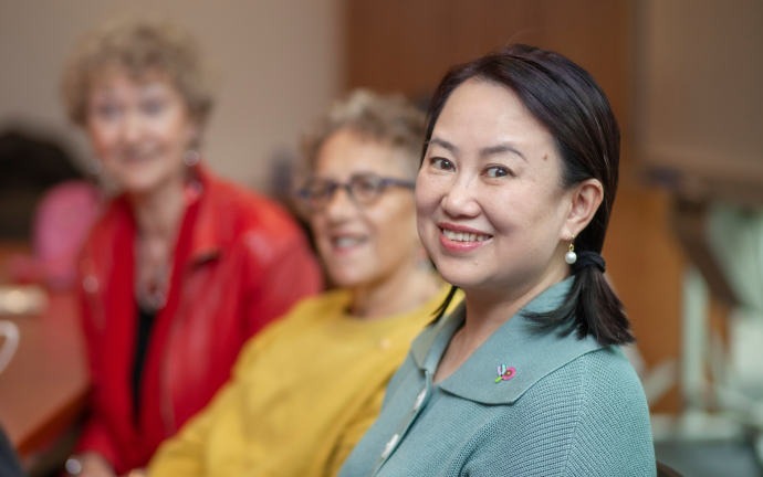 three women speaking with one them in focus and smiling at the camera