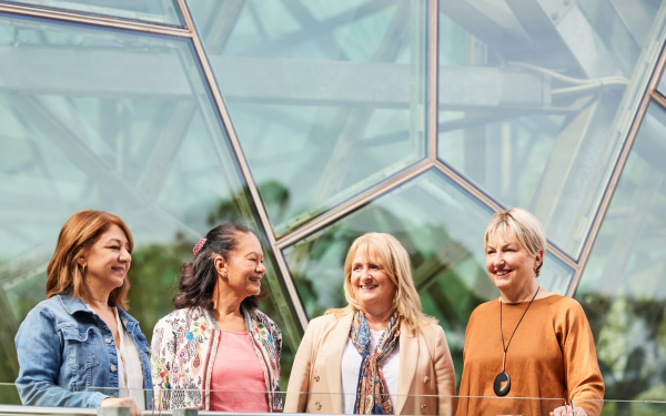4 middle aged women in conversation, standing in front of Federation Square in Melbourne